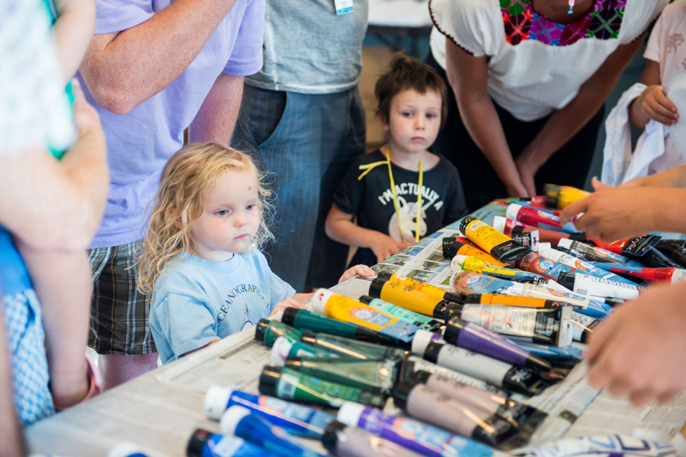 From left, Claire Dunploy, 3, and Jane Grye, 3, listen to instructions and choose paint colors to create their fish-inspired fashions.