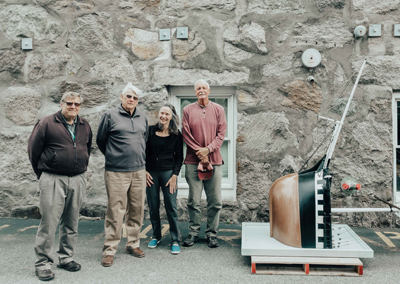 From left, Bill Brosseau (MBL Facilities), Myron Hartford, Debbie Scanlon, and Jim Baker of Bourne (Woods Hole Historical Museum, boat shop volunteer) with the restored Charles W. Morgan model before its remounting on MBL Candle House.