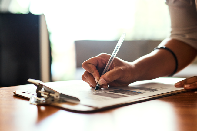 Woman writing on form with clipboard.