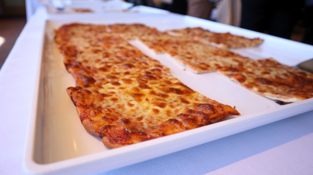 Rectangular slices of pizza sit on a white tray.