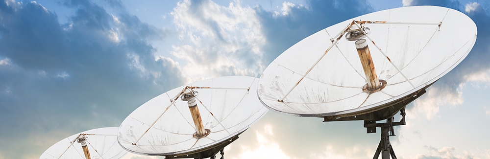 three satellite dishes pointed towards sky