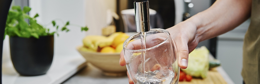 Woman pouring water into a glass from faucet.