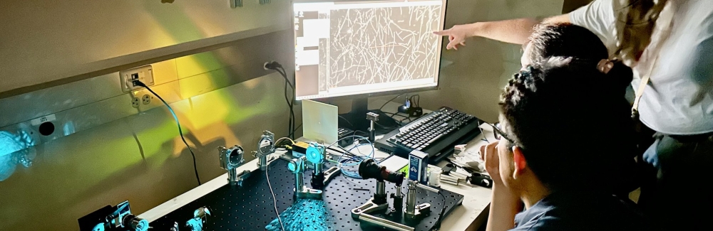 Three 2024 Physiology course students working with a self-built microscope and looking at a monitor.