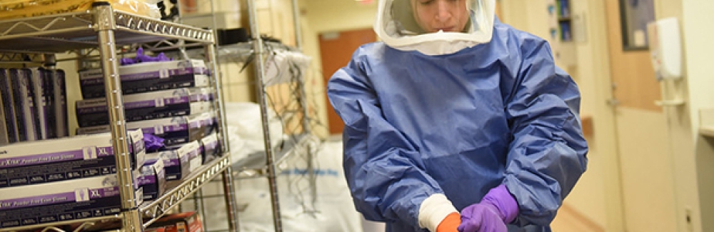 A medical worker dons personal protective equipment.