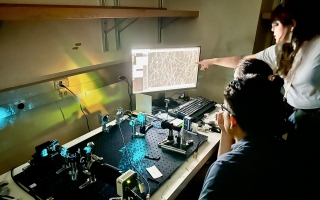 Three 2024 Physiology course students working with a self-built microscope and looking at a monitor.