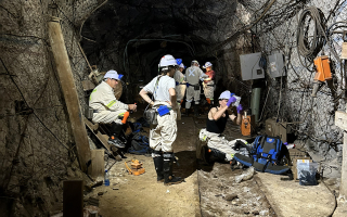 Six scientists with headlamps taking water samples from rock fractures in a South African goldmine. 