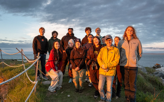 A group of people standing on a hill overlooking the ocean.