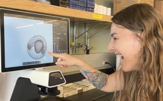 A scientist grins while examining an embryo.