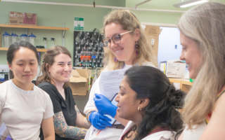 Scientists gather around a computer in the lab.