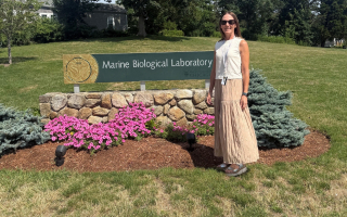 Shari Eberts stands in front of the MBL Sign. 