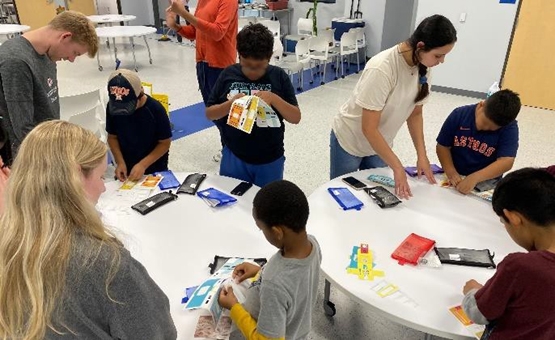 Volunteers guide the children in folding their foldscopes.