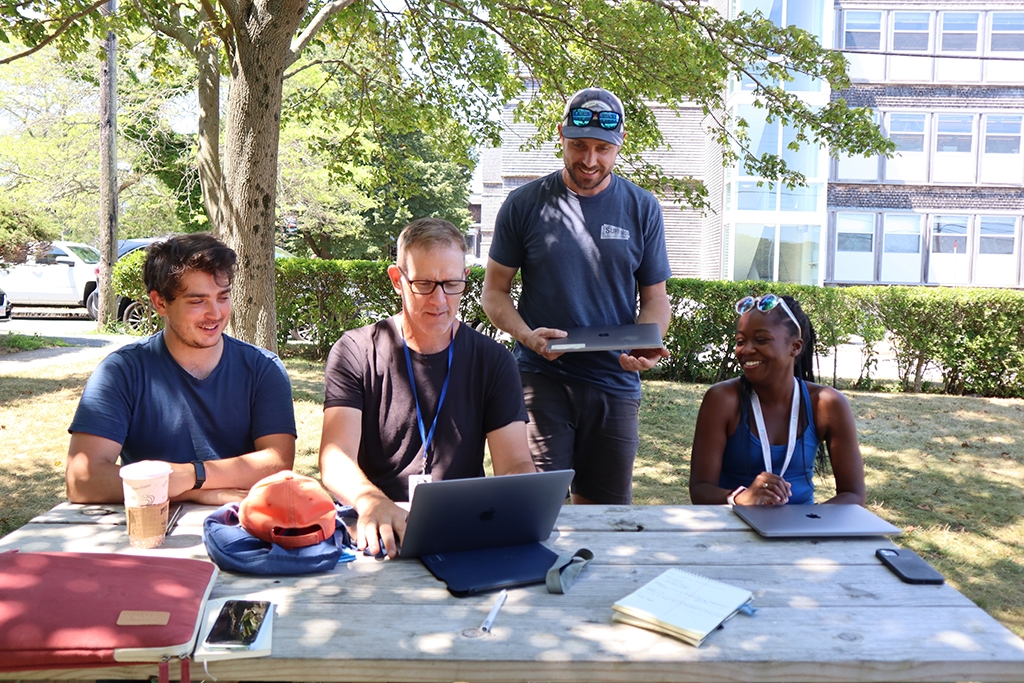 JP Riggle, Brian Prendergast, Scott Bennett and Jharnae Love discuss striped bass outside at the MBL.