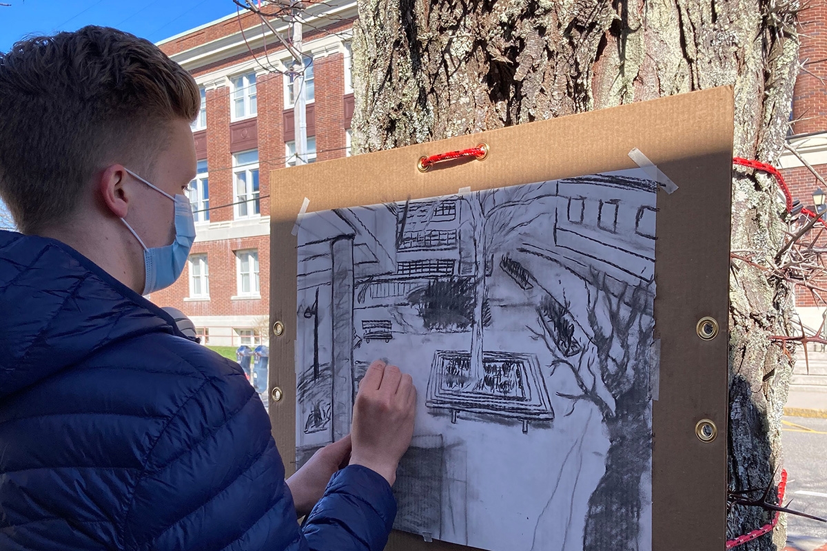 UChicago student Branson Scott-Starr doing a charcoal drawing in the MBL Quad.