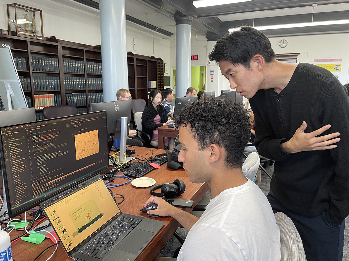 Deep Learning@MBL student Sammy Hansali of Tufts University shows his data on 2D cell tracking over time to student Justin Paek of Cornell University.