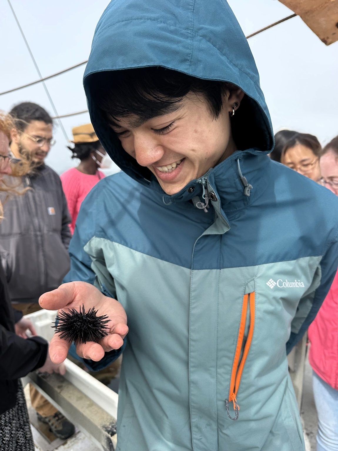 Student smiles down at sea urchin held in his hand