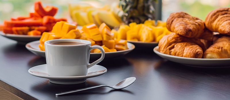 Coffee, pastries and fruit on a table.