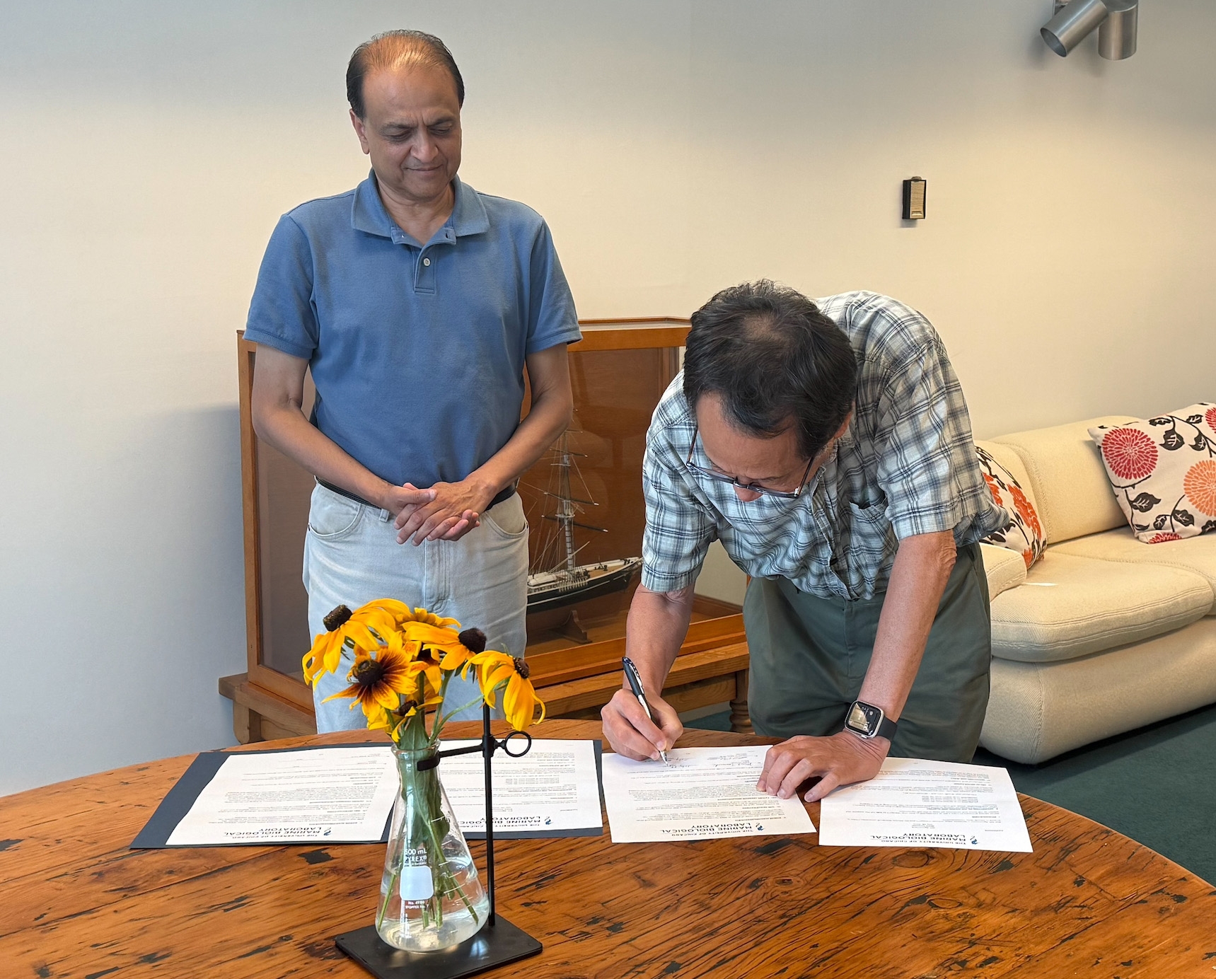 Nipam Patel looks on as Mark Terasaki signs gift agreement.