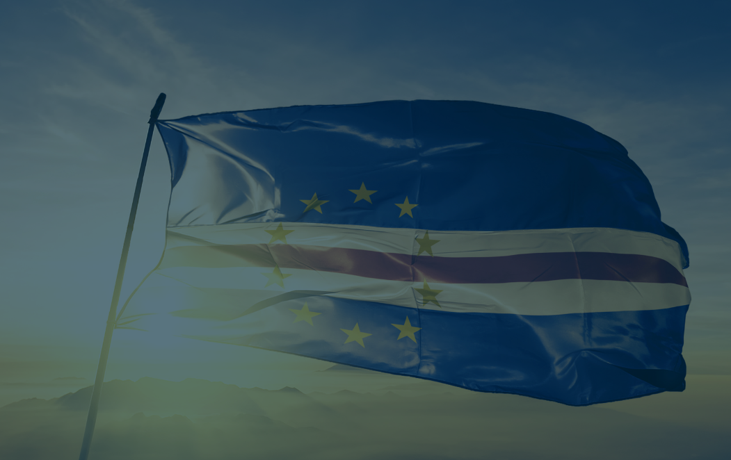 Cape Verdean flag flying with the sun behind it.