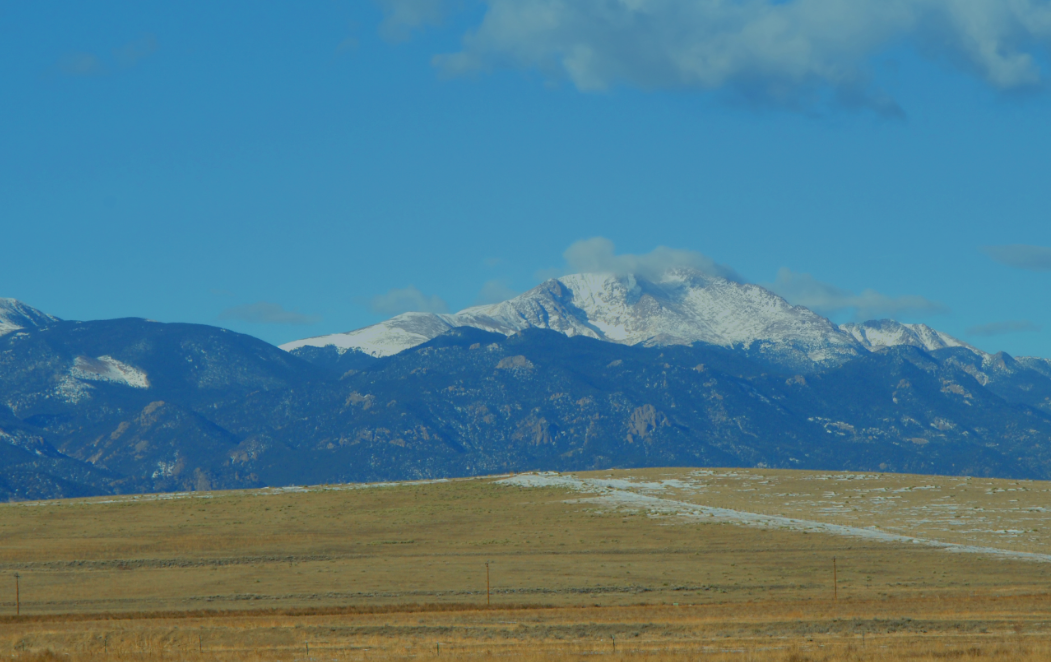 Pikes Peak with snow on top, and fields in front.