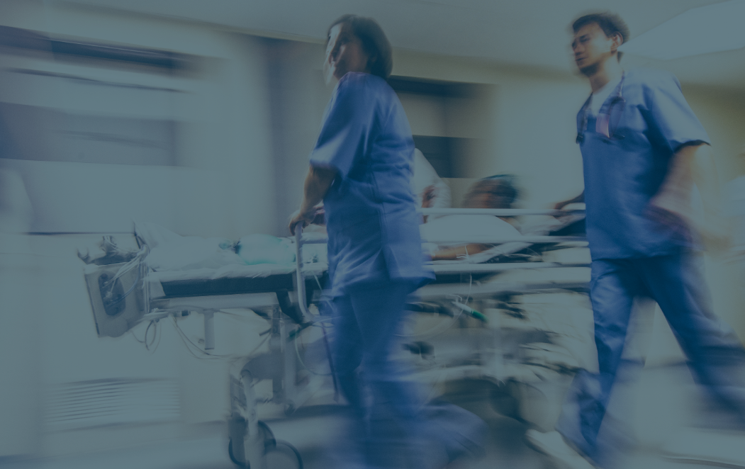 Two people wheeling a gurney in a hospital.