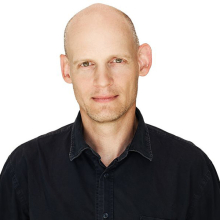 Male presenting person wearing a dark shirt.