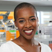 Smiling, female presenting person in a lab.