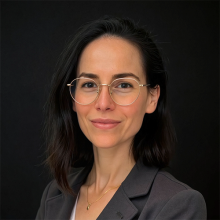 Female presenting person with long dark hair and wearing glasses.