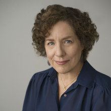 Female presenting person with short, curly brown hair.