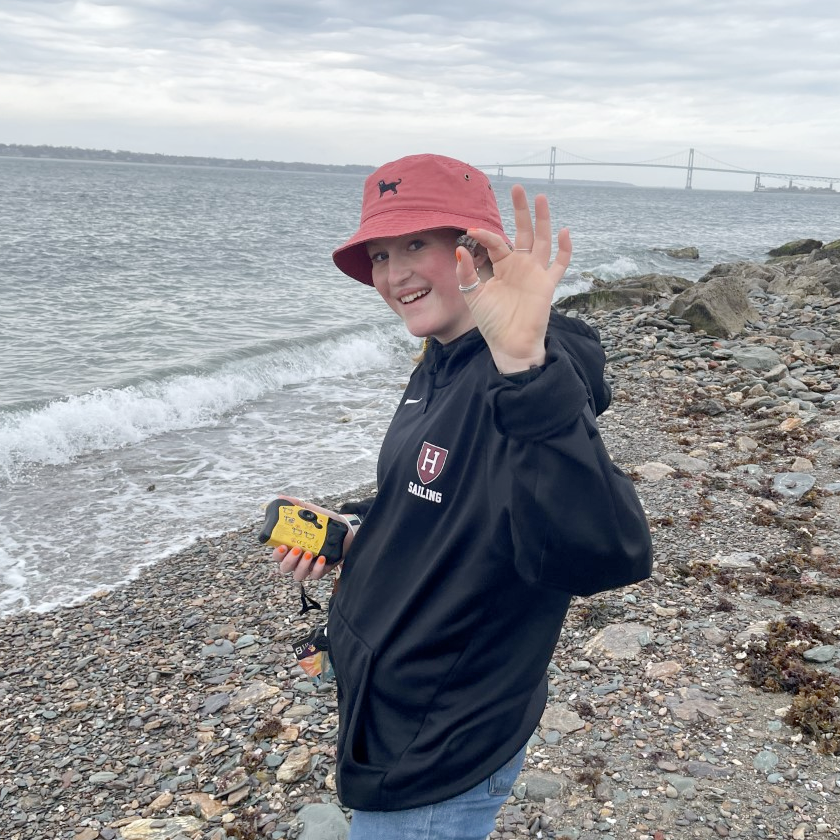 Intern Julia O'Connor holding up a shell at a beach. 